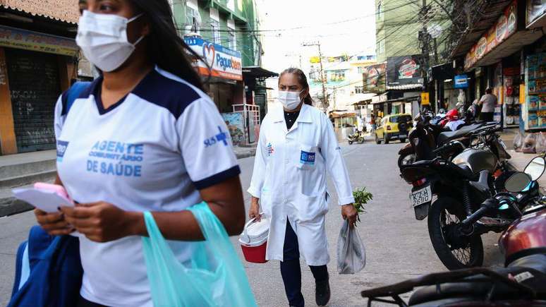 Agente comunit&aacute;ria de sa&uacute;de e enfermeira caminham na Rocinha, no Rio, durante a pandemia de covid-19
