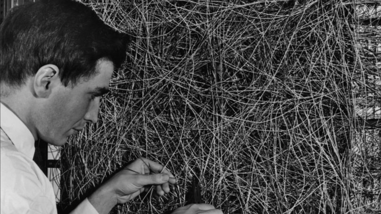 Homem ajusta fiação de máquina projetada para usar um tipo de rede neural, na década de 60