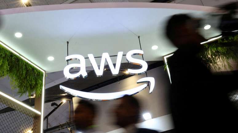 Pessoas passam em frente ao estande da Amazon Web Services (AWS) durante o Congresso Mobile da &Iacute;ndia 2025, realizado no centro de conven&ccedil;&otilde;es Yashobhoomi, em Nova D&eacute;lhi, em 8 de outubro de 2025.