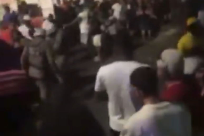 Um policial militar é visto usando o cassetete para acertar uma pessoa durante a festa