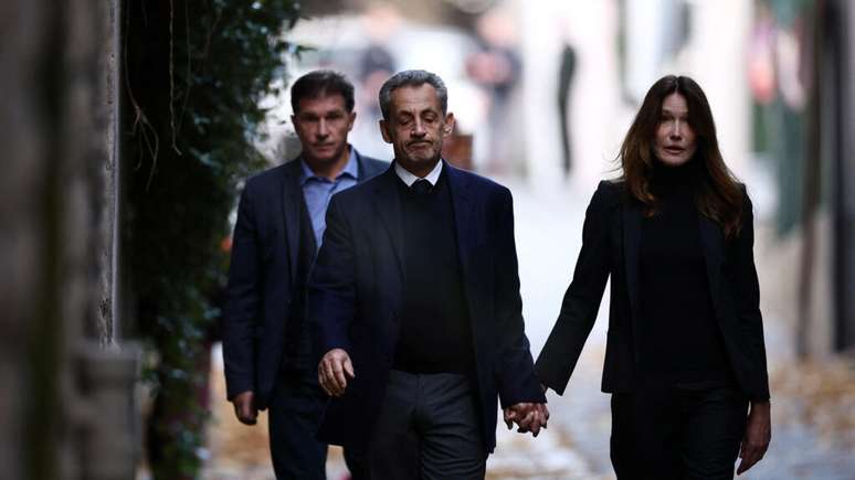 O ex-presidente francês, Nicolas Sarkozy, deixa sua casa com a esposa Carla Bruni, no dia da sua prisão, terça-feira, 21 de outubro de 2025.