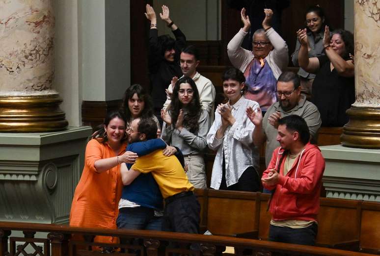 Florencia Salgueiro, vestida de laranja, comemora com a m&atilde;e e outros integrantes do grupo Empat&iacute;a Uruguay a aprova&ccedil;&atilde;o da lei de eutan&aacute;sia no Congresso uruguaio