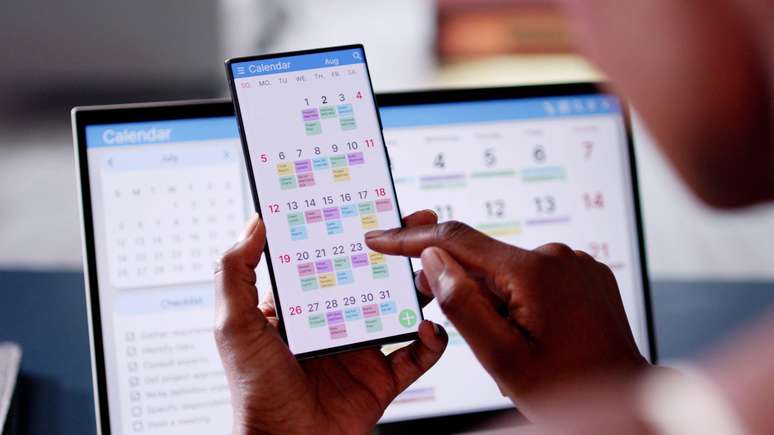 A person looking at a calendar on their cell phone full of appointments. A person looking at a calendar on their cell phone full of appointments.