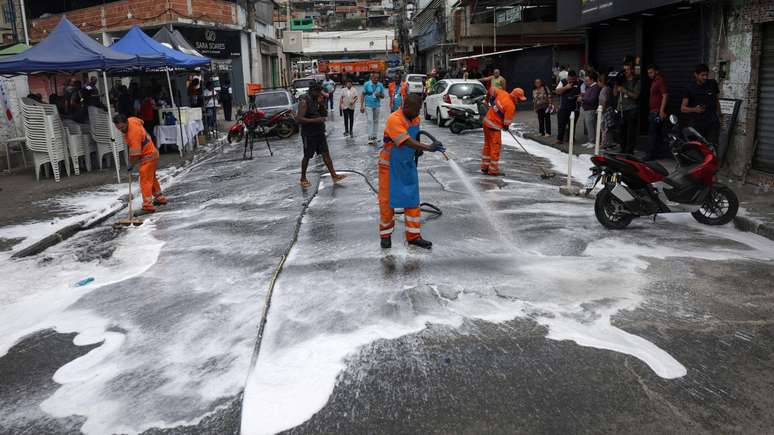Funcion&aacute;rios da Prefeitura lavam uma rua na favela da Penha no Rio de Janeiro.