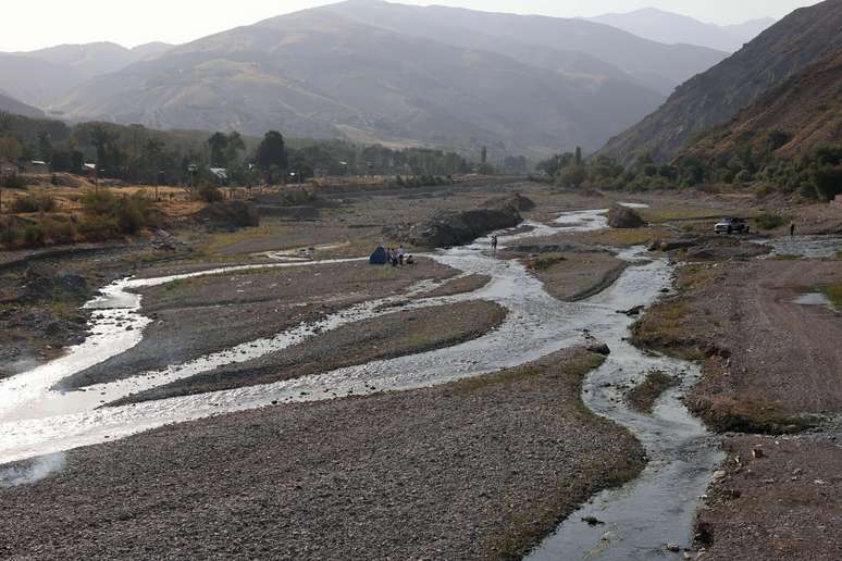 Pessoas fazem piquenique no leito quase seco de um rio na região de Fasham, ao norte de Teerã, no dia 25 de agosto. O rio, anteriormente, era cheio de água.