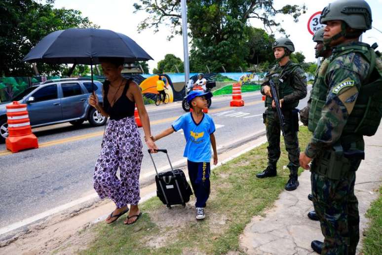 Criança observa agentes de segurança em rua de Belém, sede da COP-30