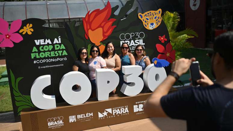 Turistas diante do símbolo da COP30 em Belém.