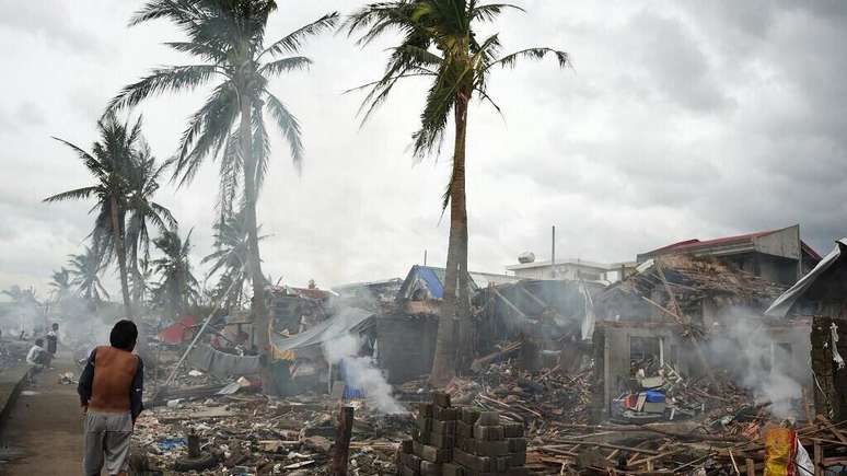 Residents burn wood from destroyed homes near the coastal sea wall in Jarchitorena in Camarines Sur province, south of Manila, on November 10, 2025, a day after Typhoon Phung Wong made landfall in the area.