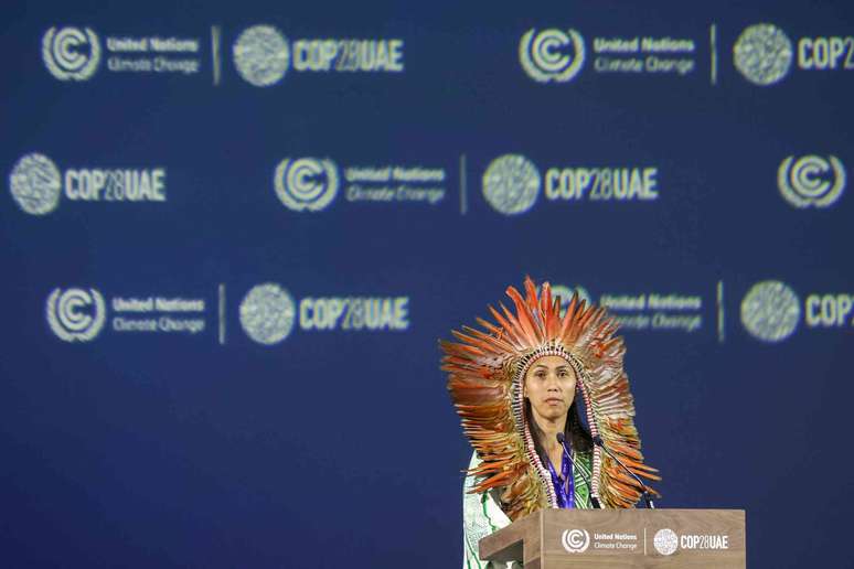 Mulher com uma tiara com penas em um púlpito da COP28