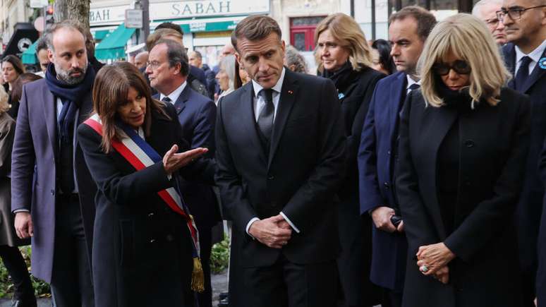 O presidente da associação de vítimas Life for Paris, Arthur Dénouveaux, a prefeita de Paris, Anne Hidalgo, o presidente da França, Emmanuel Macron, a presidente da Assembleia Nacional Francesa, Yaël Braun-Pivet, o primeiro-ministro francês, Sébastien Lecornu, a esposa do presidente francês, Brigitte Macron, e o ministro do Interior da França, Laurent Nuñez, prestam homenagem às vítimas em frente ao bar “Le Comptoir Voltaire", alvo do comando jihadista de 13 de novembro.