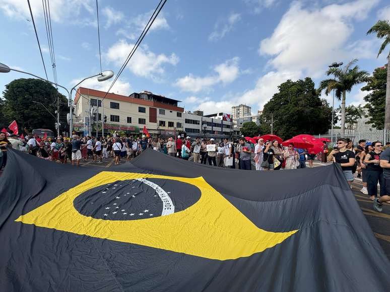 Participantes estendem a bandeira do Brasil durante a Marcha Global pelo Clima em Belém (PA), neste domingo, 15
