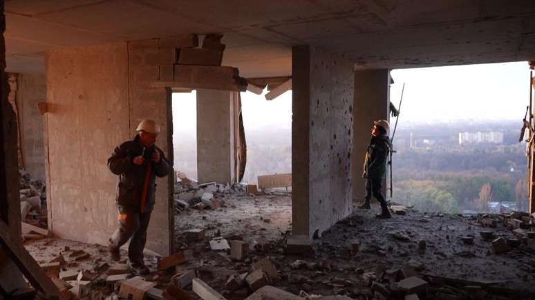 Bombeiros examinam os restos de um pr&eacute;dio de apartamentos danificado em Kiev