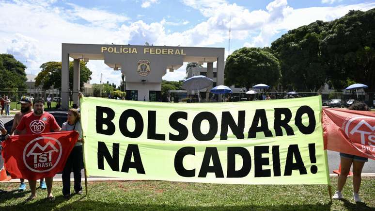 Membros do Movimento dos Trabalhadores Sem-Teto (MTST) exibem faixa diante da superintendência da Polícia Federal, em Brasília, onde o ex-presidente Jair Bolsonaro está preso preventivamente. Brasília, 22 de novembro de 2025.