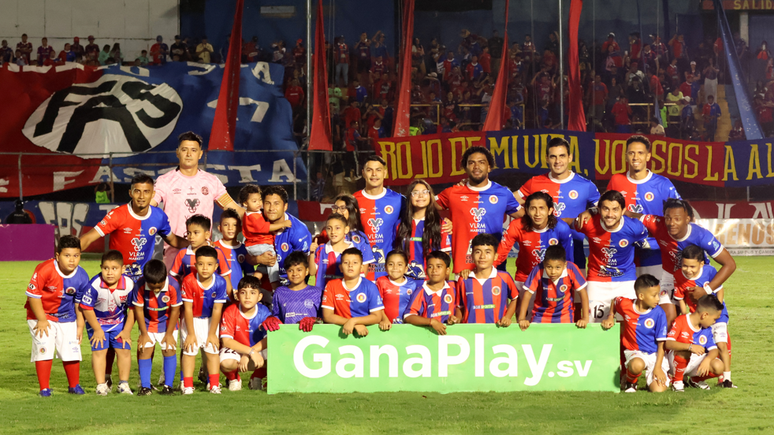 Os jogadores do FAS posam com seus filhos e outras crian&ccedil;as antes da partida contra o Municipal Lime&ntilde;o: o FAS &eacute; uma das tr&ecirc;s equipes da Primeira Divis&atilde;o de El Salvador a usar as camisas 13 ou 18