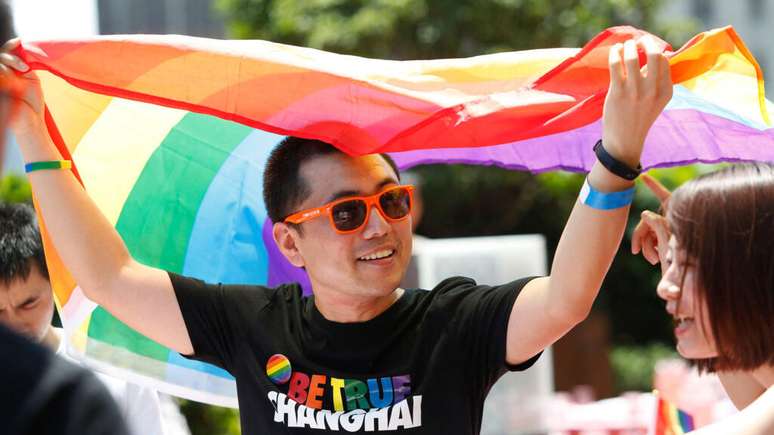 A Pride Parade participant in Shanghai, China, holding a rainbow flag, June 17, 1917.