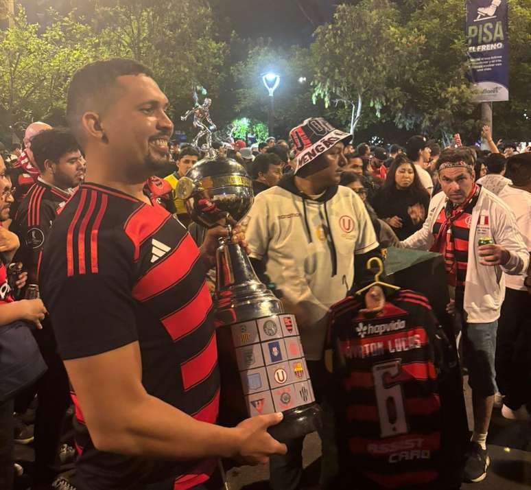 A Universitario fan takes the Libertadores Cup to Flamengo fans
