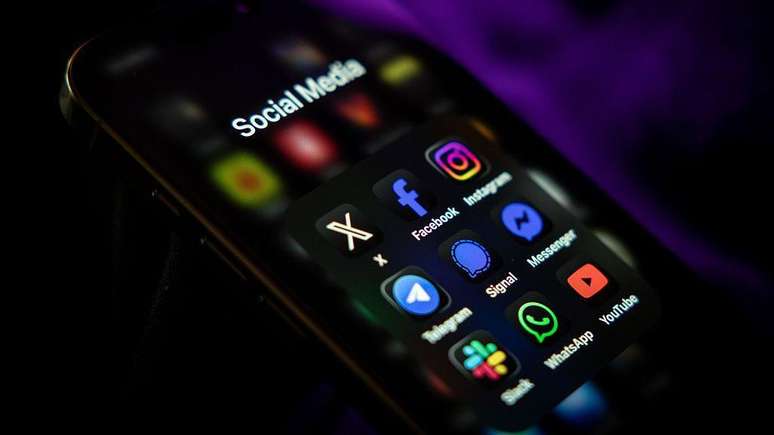 Telefone celular mostrando ícones de redes sociais e aplicativos de mensagens na tela