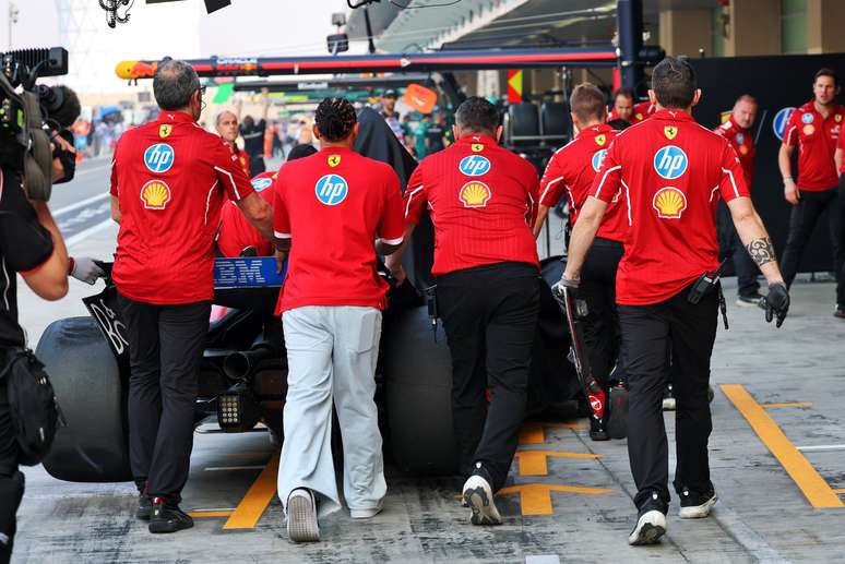 Lewis Hamilton ajuda equipe a empurrar seu carro de volta para garagem