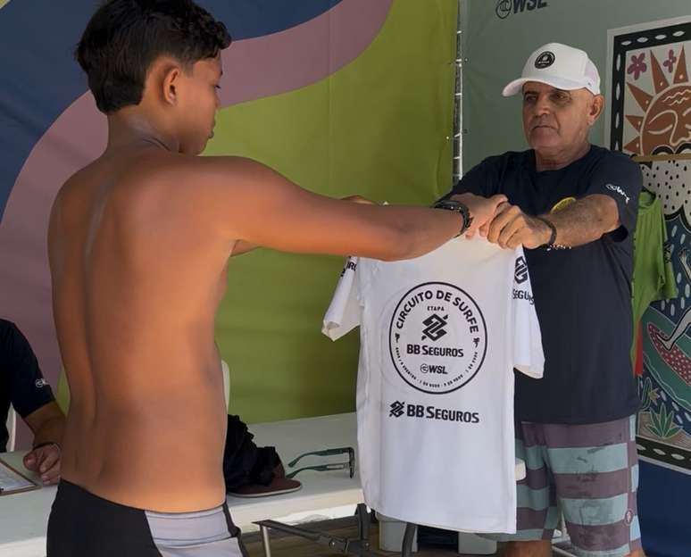 Carlos Franco, beach marshall da etapa da WSL em Fortaleza, entrega lycra para competidor no primeiro dia do torneio