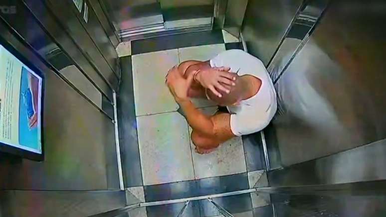 Alex aparece sozinho e transtornado no elevador, após Katiane cair do 10º andar