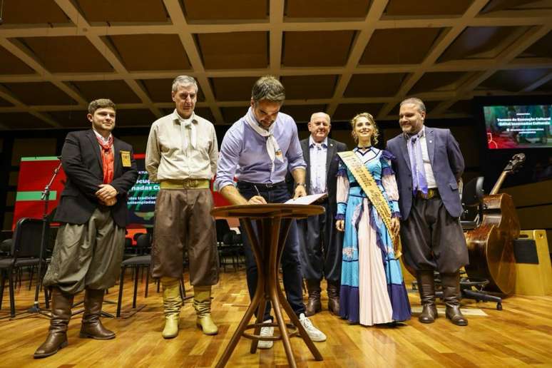 Foto mostra governador Eduardo Leite assinando documento