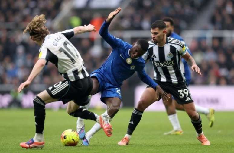 - George Wood/Getty Images - Legenda: Caicedo, do Chelsea, disputa a jogada com Bruno Guimar&atilde;es (39) e Gordon, do Newcastle