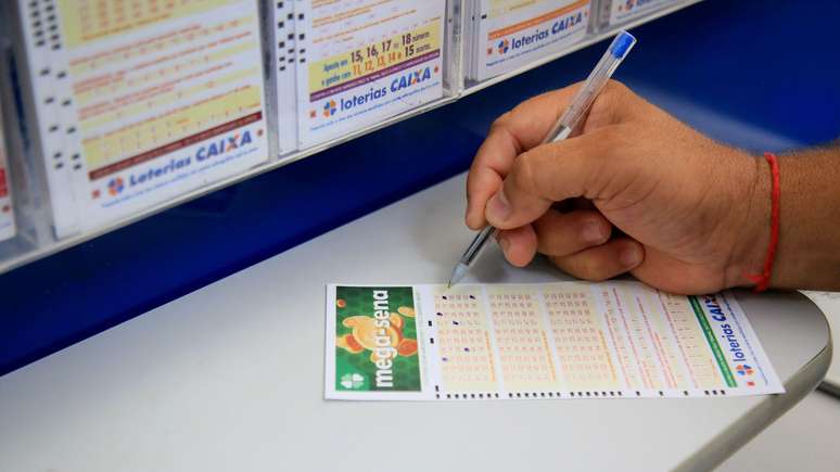 Uma pessoa faz apostas na ficha da Mega Sena.