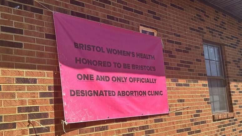 Uma placa rosa pendurada em um pr&eacute;dio de tijolos diz: &ldquo;A Bristol Women&rsquo;s Health tem a honra de ser a &uacute;nica cl&iacute;nica de aborto oficialmente designada de Bristol&rdquo;.

