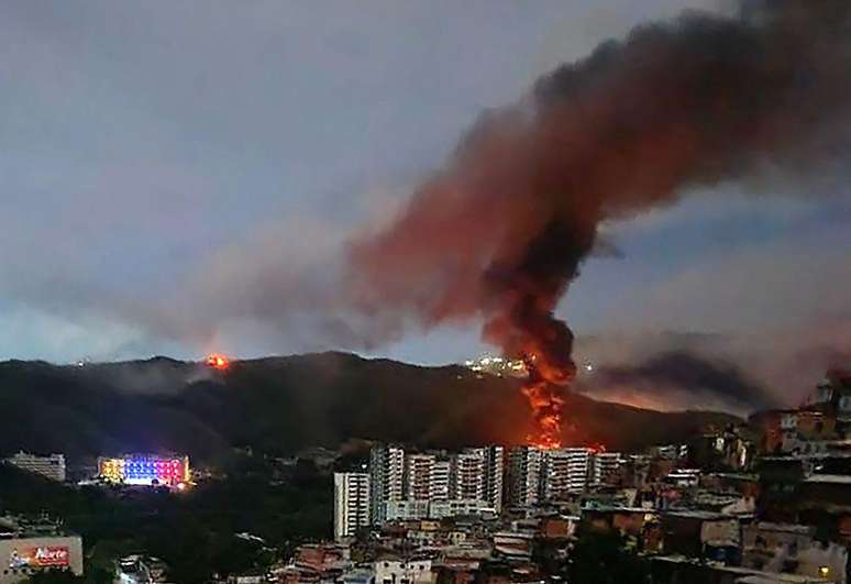 Um inc&ecirc;ndio no Forte Tiuna, o maior complexo militar da Venezuela, &eacute; visto &agrave; dist&acirc;ncia ap&oacute;s uma s&eacute;rie de explos&otilde;es em Caracas, em 3 de janeiro de 2026