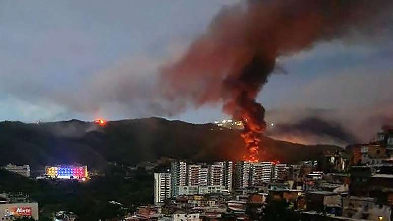 Um inc&ecirc;ndio em Fuerte Tiuna, o maior complexo militar da Venezuela, &eacute; observado &agrave; dist&acirc;ncia ap&oacute;s uma s&eacute;rie de explos&otilde;es em Caracas, em 3 de janeiro de 2026.