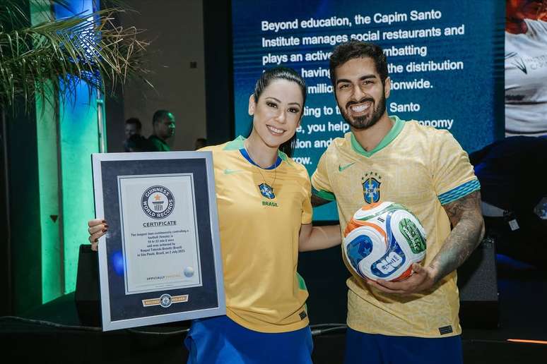 Ricardinho posa com Raquel Freestyle, juntos, eles mostram placa do Guiness