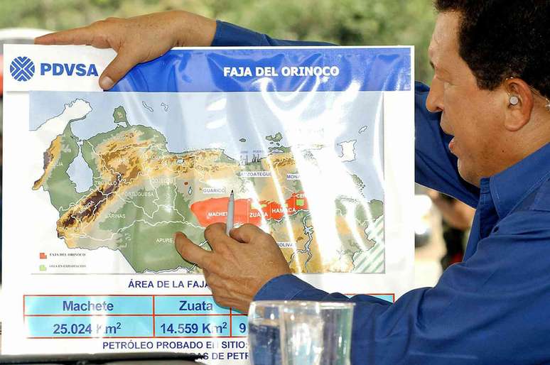Homem segura um mapa detalhado com o logotipo da PDVSA.