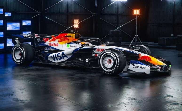 A imagem mostra o novo carro da Racing Bulls para 2026 em um est&uacute;dio moderno. O design combina azul met&aacute;lico, branco e fibra de carbono, destacando os patroc&iacute;nios da Visa, Cash App e o novo motor Ford. O modelo segue as regras aerodin&acirc;micas da nova era da F1, com bico integrado e calotas nas rodas.