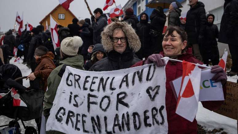 Homem e mulher seguram um cartaz com os dizeres: 'A Groenl&acirc;ndia &eacute; para os groenlandeses' durante protesto em Nuuk