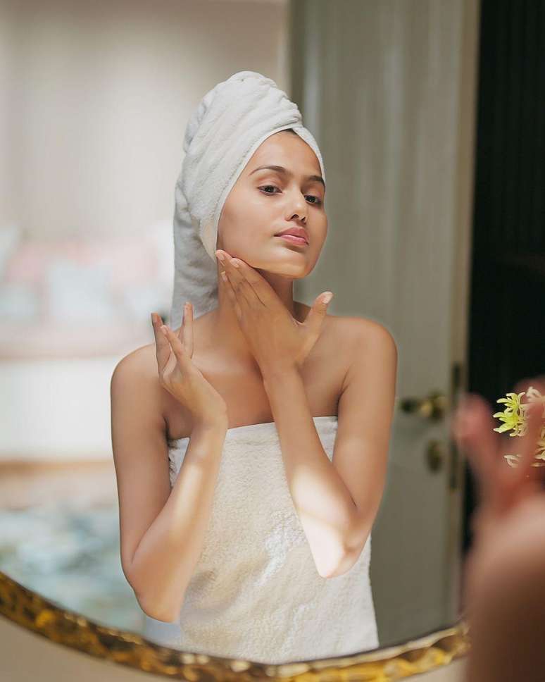 Mulher passando creme com toalha na cabe&ccedil;a.