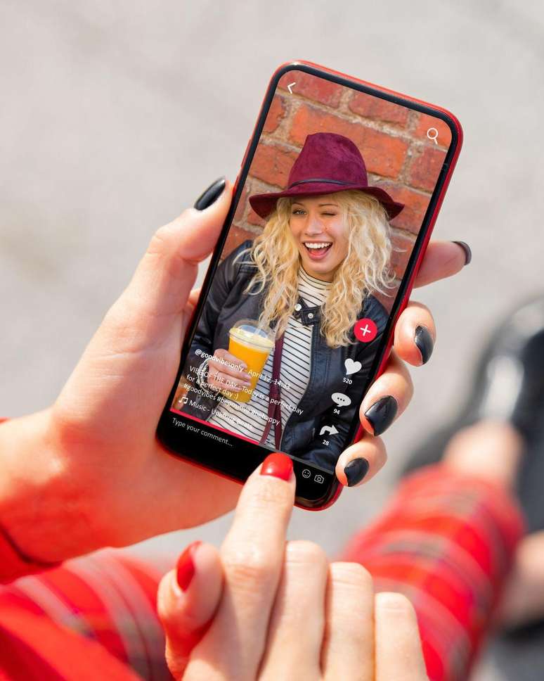 Imagem de um celular com mulher loira e cabelo cacheado sorrindo.