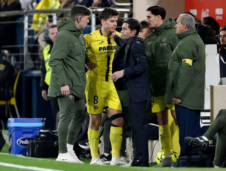 Juan Foyth deixando o campo amparado pela equipe m&eacute;dica do Villarreal.