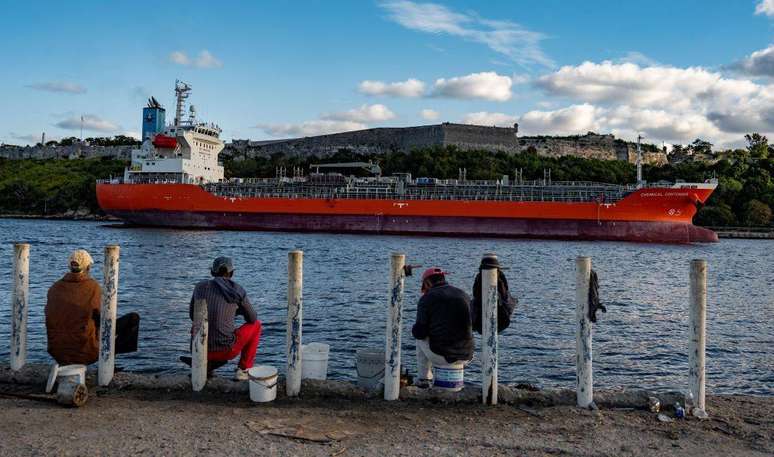 Um navio-tanque de petr&oacute;leo ao largo da costa de Havana, com pescadores observando-o ao fundo.