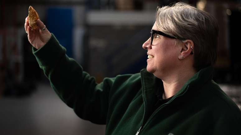 Sara Machin, respons&aacute;vel pelas descobertas da Access +, que trabalha no arquivo de p&oacute;s-escava&ccedil;&atilde;o, segurando um machado de m&atilde;o do per&iacute;odo Paleol&iacute;tico