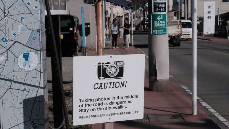 'Cuidado! Tirar fotos no meio da rua &eacute; perigoso. Permane&ccedil;a na cal&ccedil;ada', diz o cartaz em ingl&ecirc;s e japon&ecirc;s em Fujiyoshida, no Jap&atilde;o
