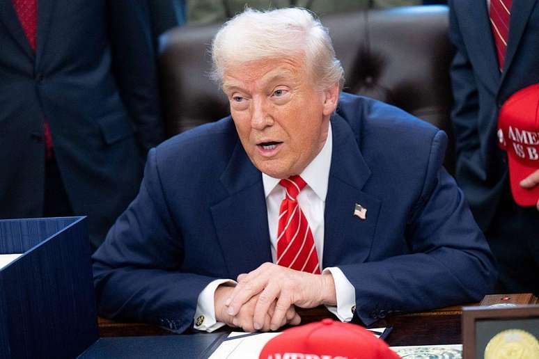 Donald Trump sentado em uma cadeira na Casa Branca.