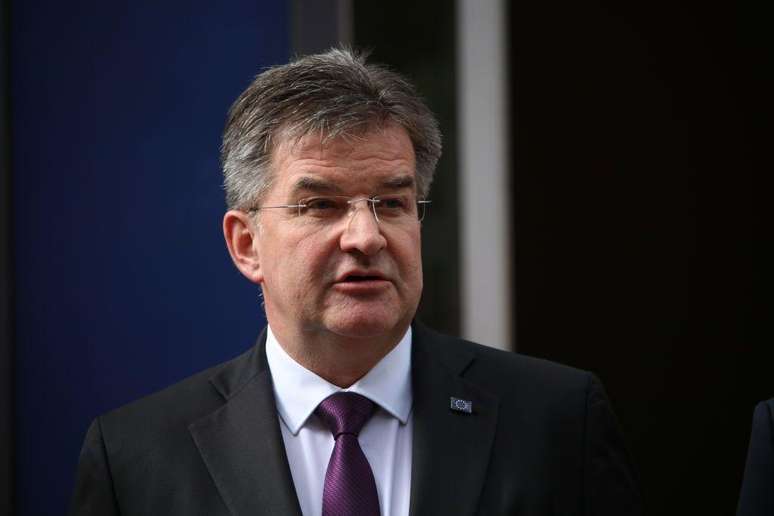 Miroslav Lajč&aacute;k usando terno preto e uma gravata roxa. Ele tamb&eacute;m usa &oacute;culos de grau e tem cabelos grisalhos.