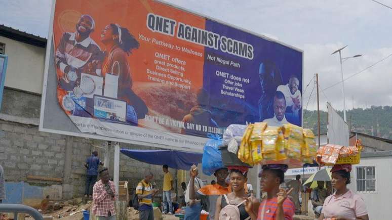 Cartazes como este, com a inscri&ccedil;&atilde;o 'QNET contra os golpes', tentam alertar a popula&ccedil;&atilde;o da &Aacute;frica ocidental sobre os criminosos que se fazem passar por recrutadores da empresa