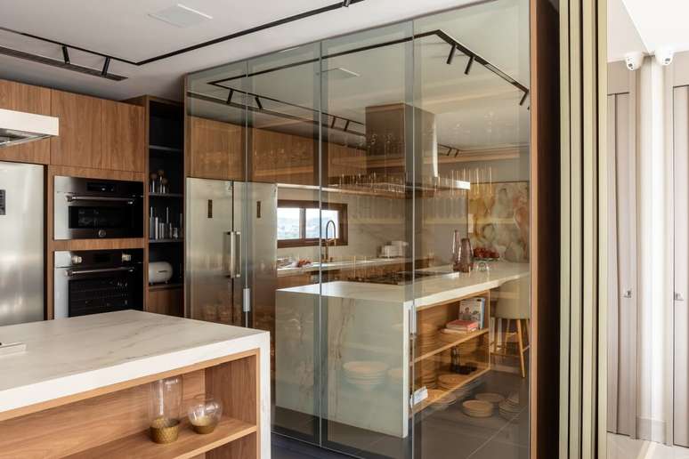 O uso do vidro espelhado valoriza a cristaleira, destaca a ilumina&ccedil;&atilde;o interna e equilibra profundidade e transpar&ecirc;ncia no ambiente Projeto: Meneghisso & Pasquotto Arquitetura |