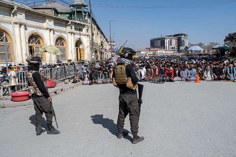 Agentes de seguran&ccedil;a do Taleb&atilde; fazem a guarda enquanto fi&eacute;is afeg&atilde;os realizam ora&ccedil;&otilde;es, com medidas de seguran&ccedil;a refor&ccedil;adas ap&oacute;s confrontos na fronteira