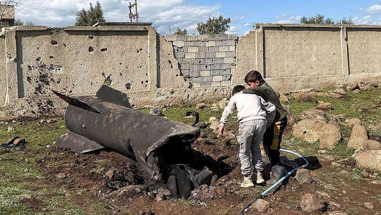 Duas crian&ccedil;as examinam um resto de um foguete iraniano que teria sido interceptado por for&ccedil;as israelenses na zona rural de Quneitra, cerca das Colinas de Gol&atilde;