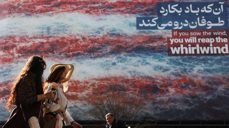 Iranianos caminham em outdoor com mensagem anti-EUA em Teer&atilde;: "Se voc&ecirc; semear o vento, colher&aacute; o vendaval"