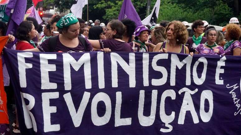 Mulheres durante manifesta&ccedil;&atilde;o segurando uma faixa "Feminismo &eacute; revolu&ccedil;&atilde;o"