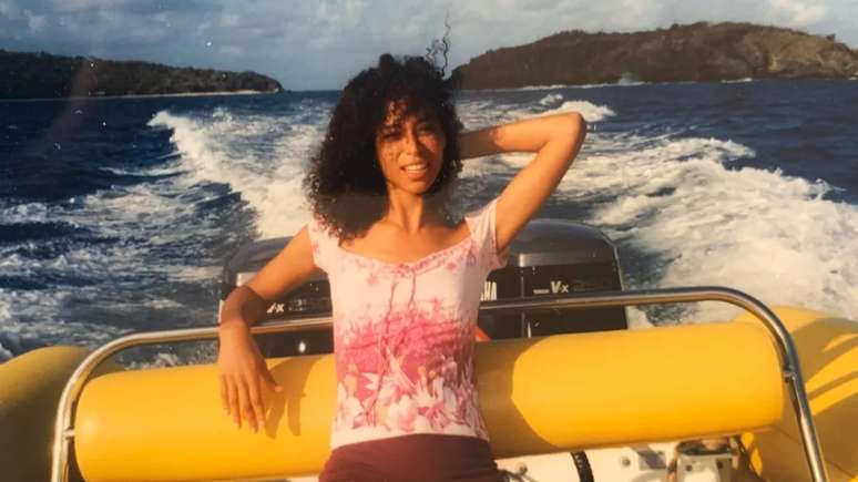 Lisa Phillips em um barco, com a ilha de Epstein ao fundo