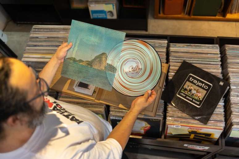 Paulo Sakae Tahira, propriet&aacute;rio da loja de discos Patu&aacute; Discos, com os &aacute;lbuns 'Trajeto' de Vitor Assis Brasil e 'Rio Oir' de Cildo Meireles